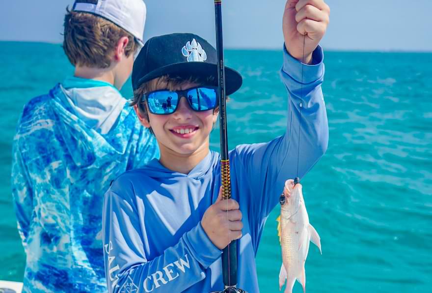 Boy happily showing a small fish caught while fishing in Grand Cayman.