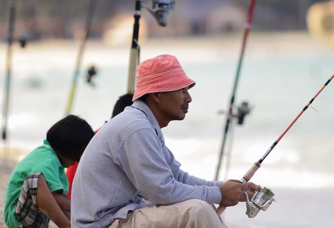 Man fishing from the shore with his family on a Cayman Island fishing trip.