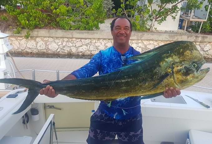 Angler holding a large mahi mahi aboard a Cayman Islands fishing charter boat