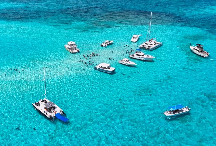 Boats anchored in a pristine turquoise bay at Stingray City in the Cayman Islands.