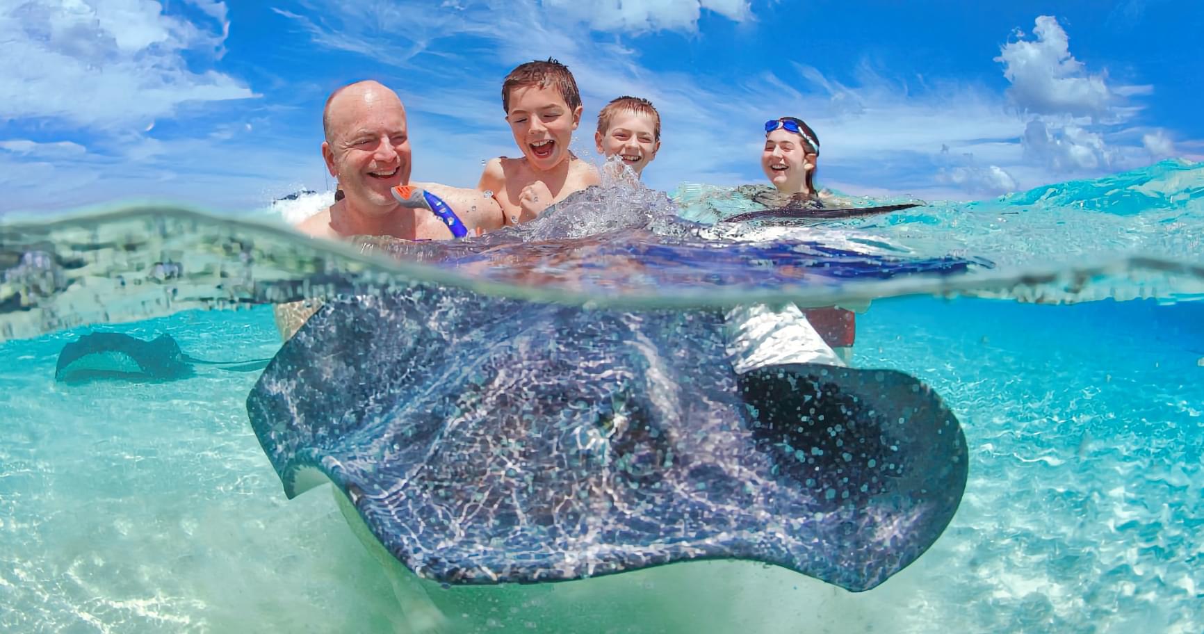 Family enjoying a close encounter at Stingray City Sandbar in Grand Cayman