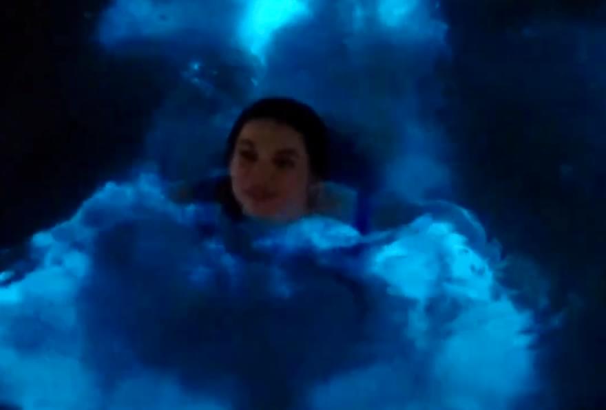 Person swimming surrounded by glowing blue bioluminescence Cayman.