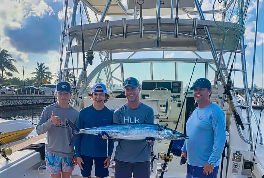 Family holding a large Wahoo fish caught during a Grand Cayman fishing licensed trip.