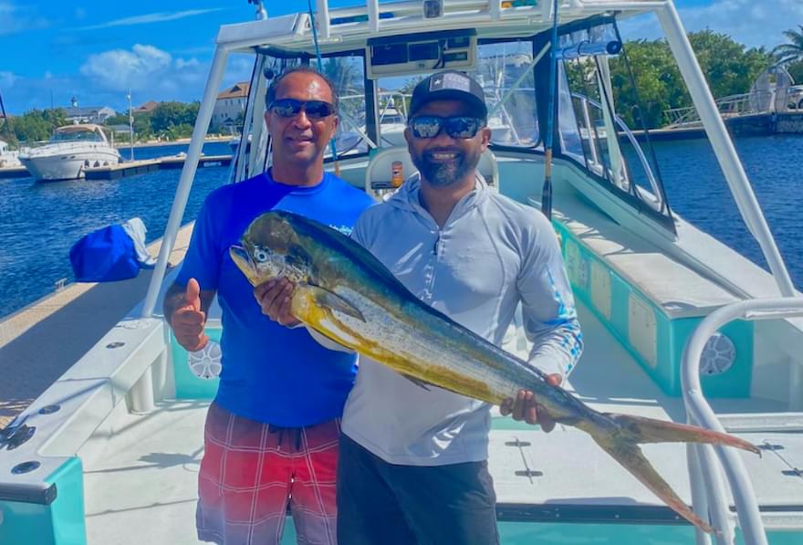Two anglers holding a mahi mahi on a boat docked with the best fishing charters in Grand Cayman
