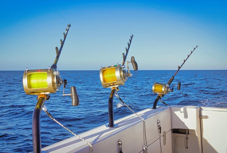 Three fishing rods set up on the back of a boat during a deep-sea fishing trip