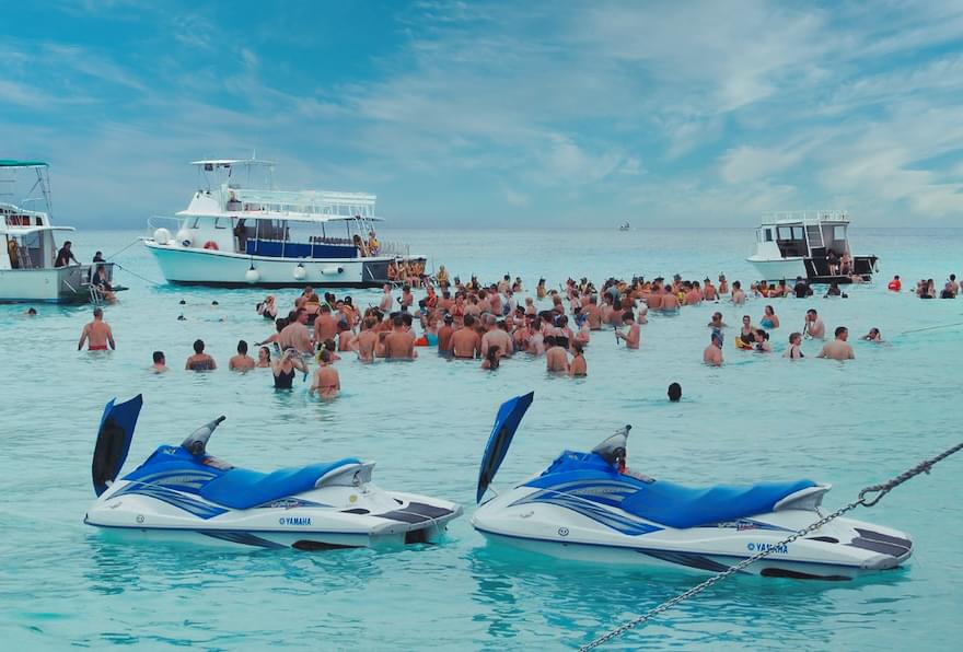 Crowd of people gathering in shallow water near jet ski cayman islands at Stingray City in the Cayman Islands.