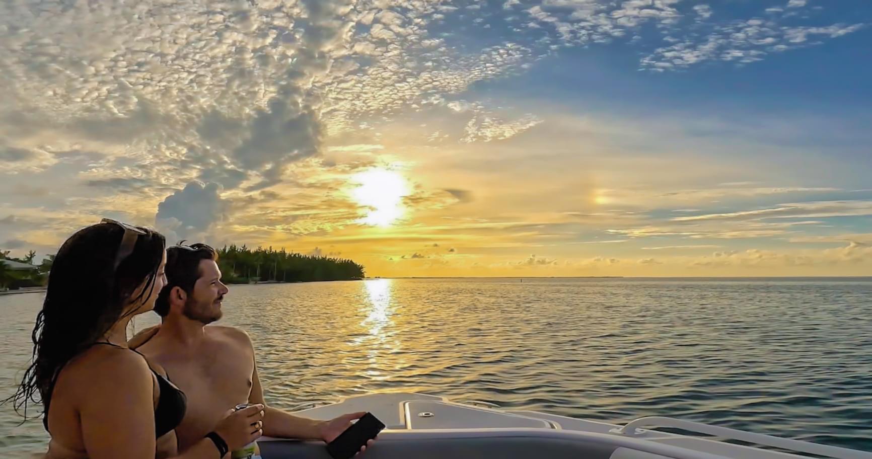 Couple watching the sunset from the front of a boat during a Grand Cayman sunset cruise.