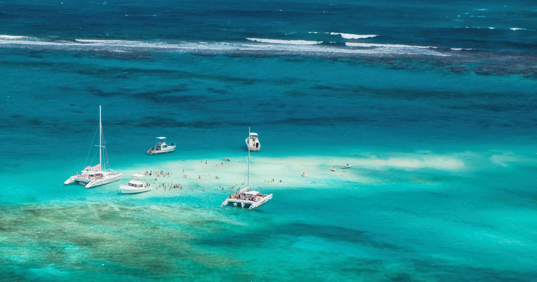 Aerial view of boats anchored near coral reefs, ideal for activities during weather forecast in Grand Cayman