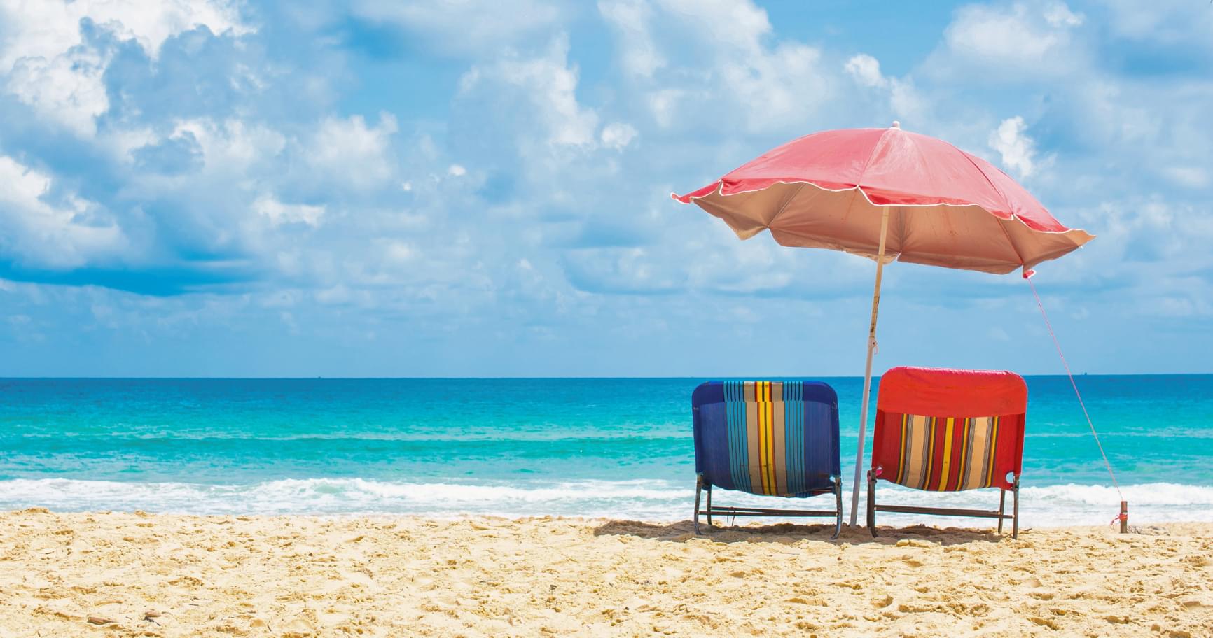 Colorful beach umbrellas on Seven Mile Beach under sunny skies highlight the best time to visit the Cayman Islands