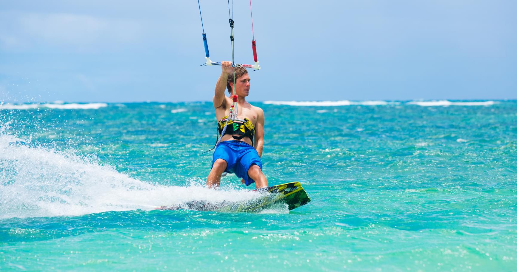 A kitesurfer gliding over turquoise waters, enjoying the Cayman Islands kitesurfing season
