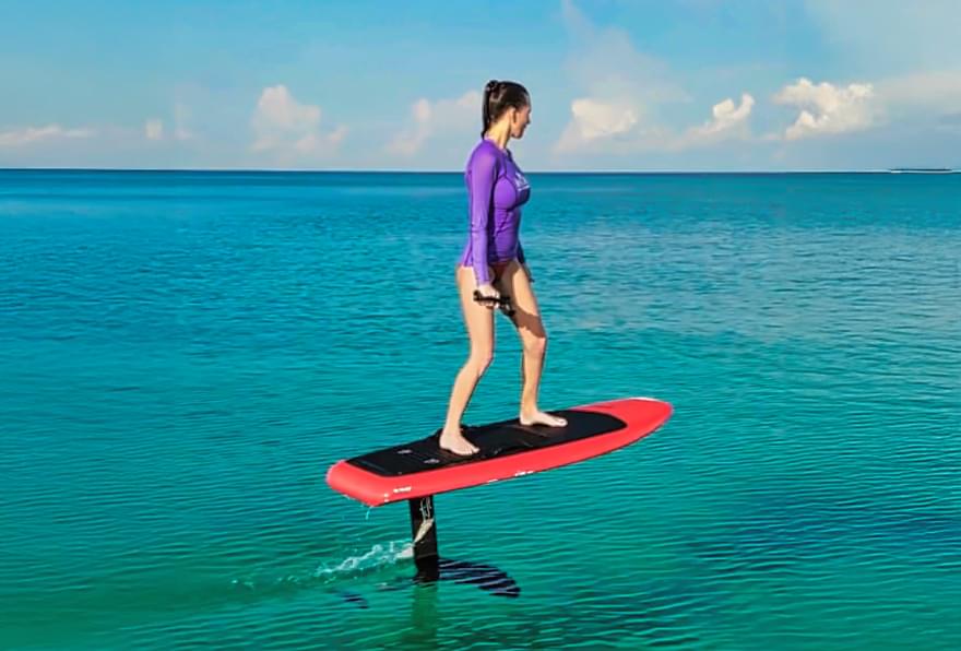 A rider on an eFoil board above calm waters near Seven Mile Beach in Grand Cayman, perfect during the Grand Cayman off-season