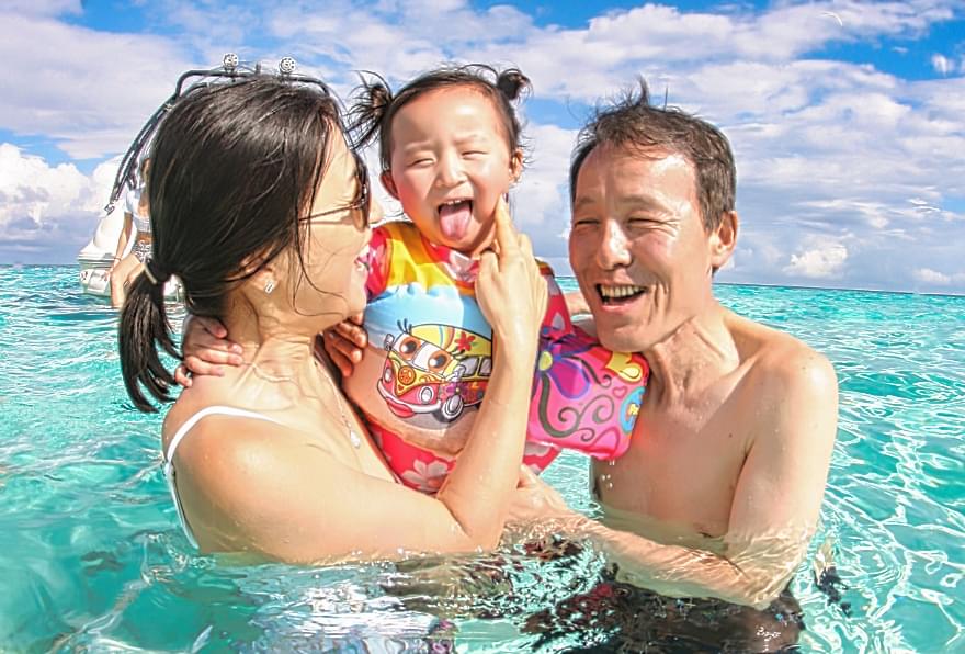 A family enjoying warm, clear waters during Grand Cayman’s best time to visit