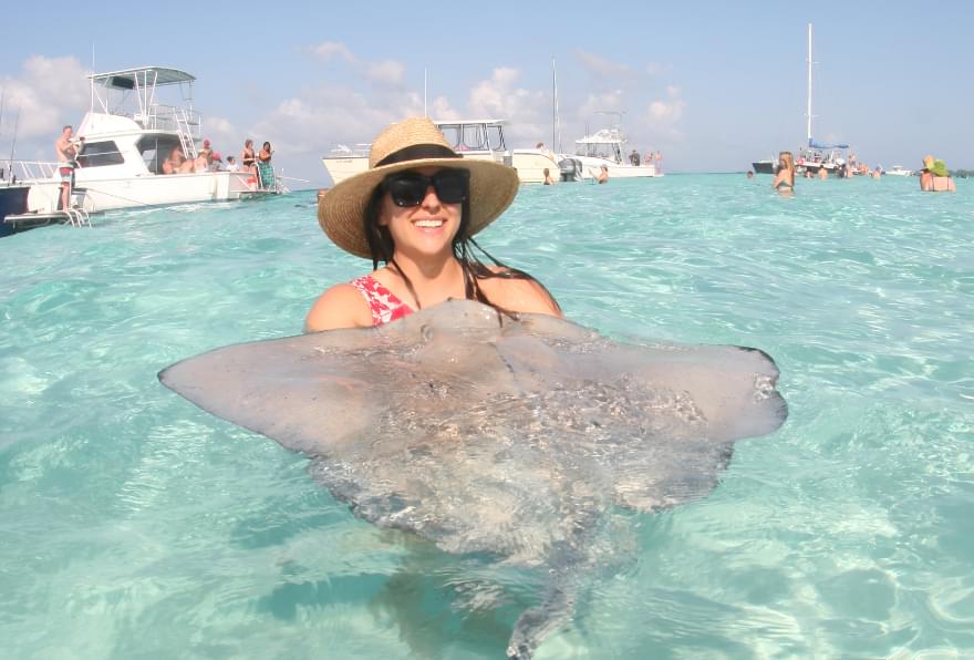 A woman holding a stingray at Stingray City, a must-visit attraction during the Cayman Islands best time to visit