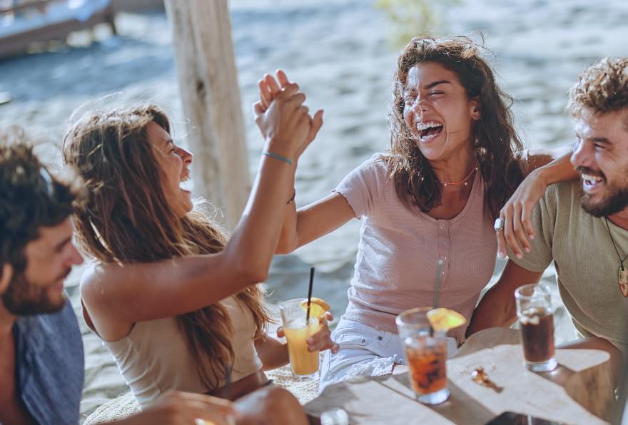 Friends toasting with tropical drinks at a beachside restaurant in Grand Cayman