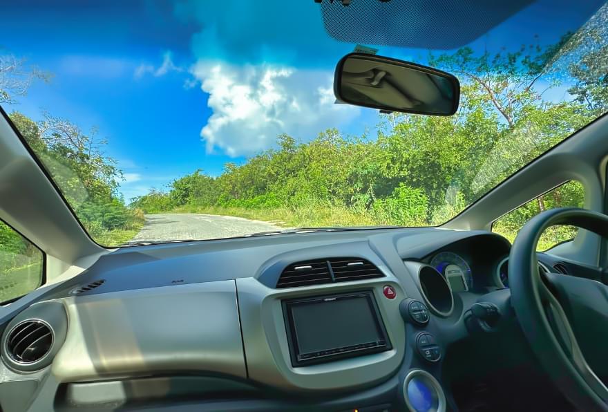 Inside view of a rental car exploring Grand Cayman’s lush landscapes, marked on a Grand Cayman Island map