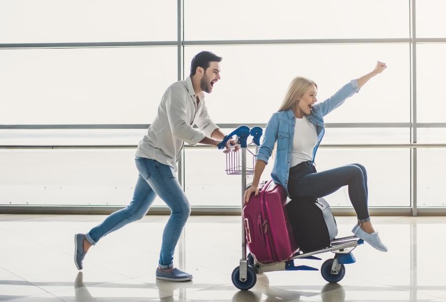 A couple joyfully rushed through an airport terminal, ready to explore the best options for how to get to Cayman Islands