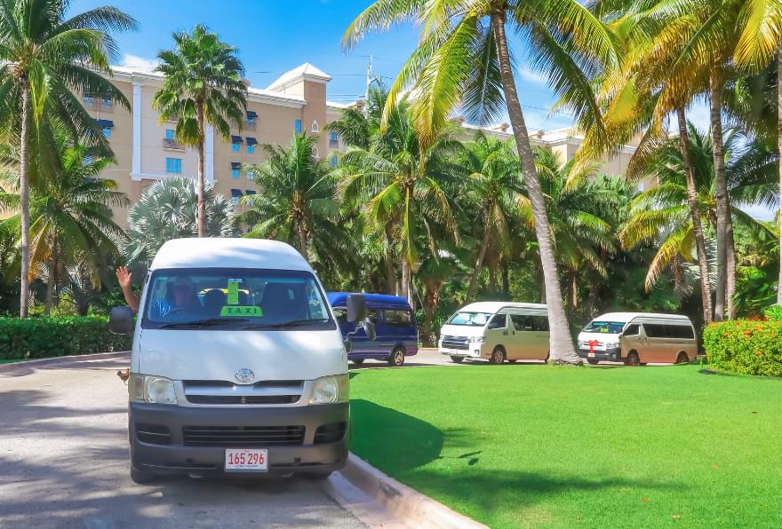 Taxi waiting under palm trees near a Grand Cayman resort, highlighting reliable taxi service Grand Cayman