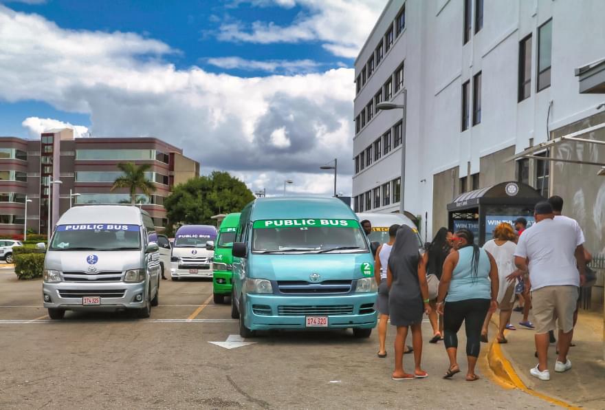 Travelers board a minivan near a bustling Grand Cayman street, showcasing options for getting around Grand Cayman