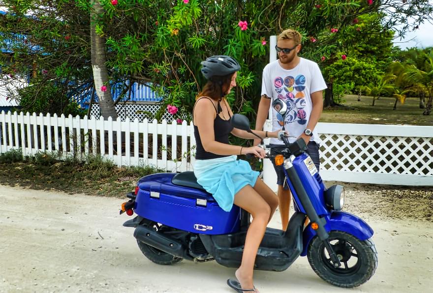 A couple on a scooter enjoying a scenic ride, demonstrating the convenience of scooter rentals in little Cayman