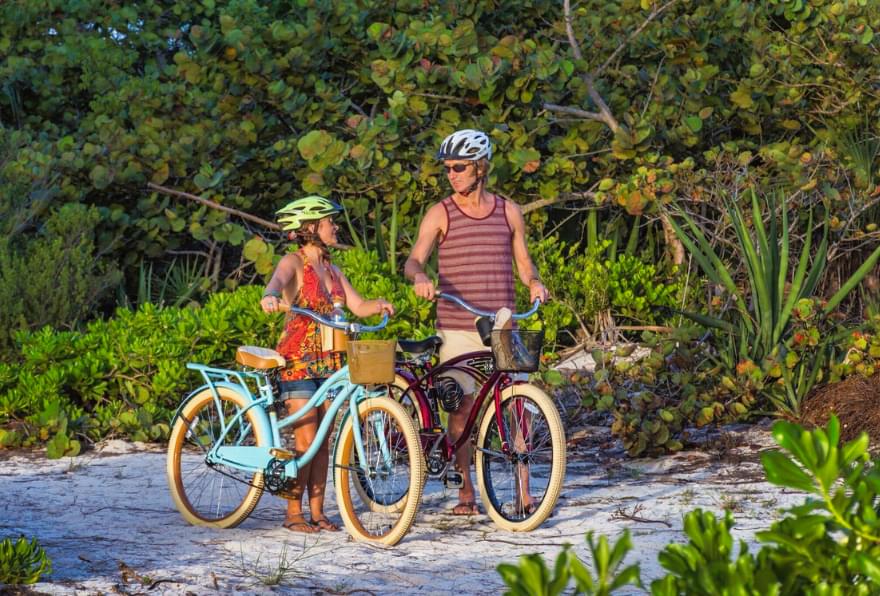 Two people cycling along a sunny trail, highlighting the benefits of choosing a Grand Cayman bike rental