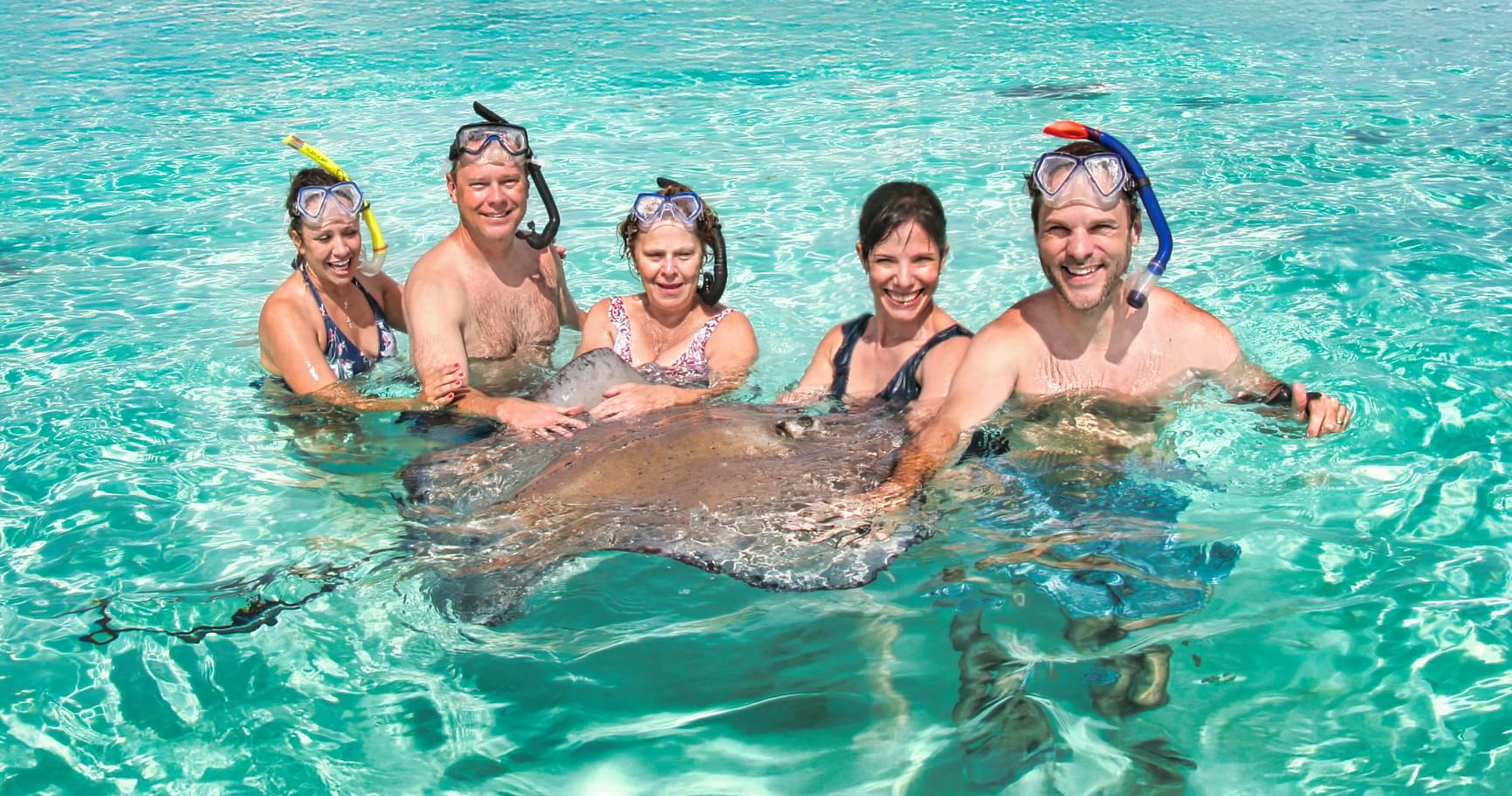 Friends floating in the crystal-clear waters of Stingray City, celebrating the best way of getting around in Grand Cayman