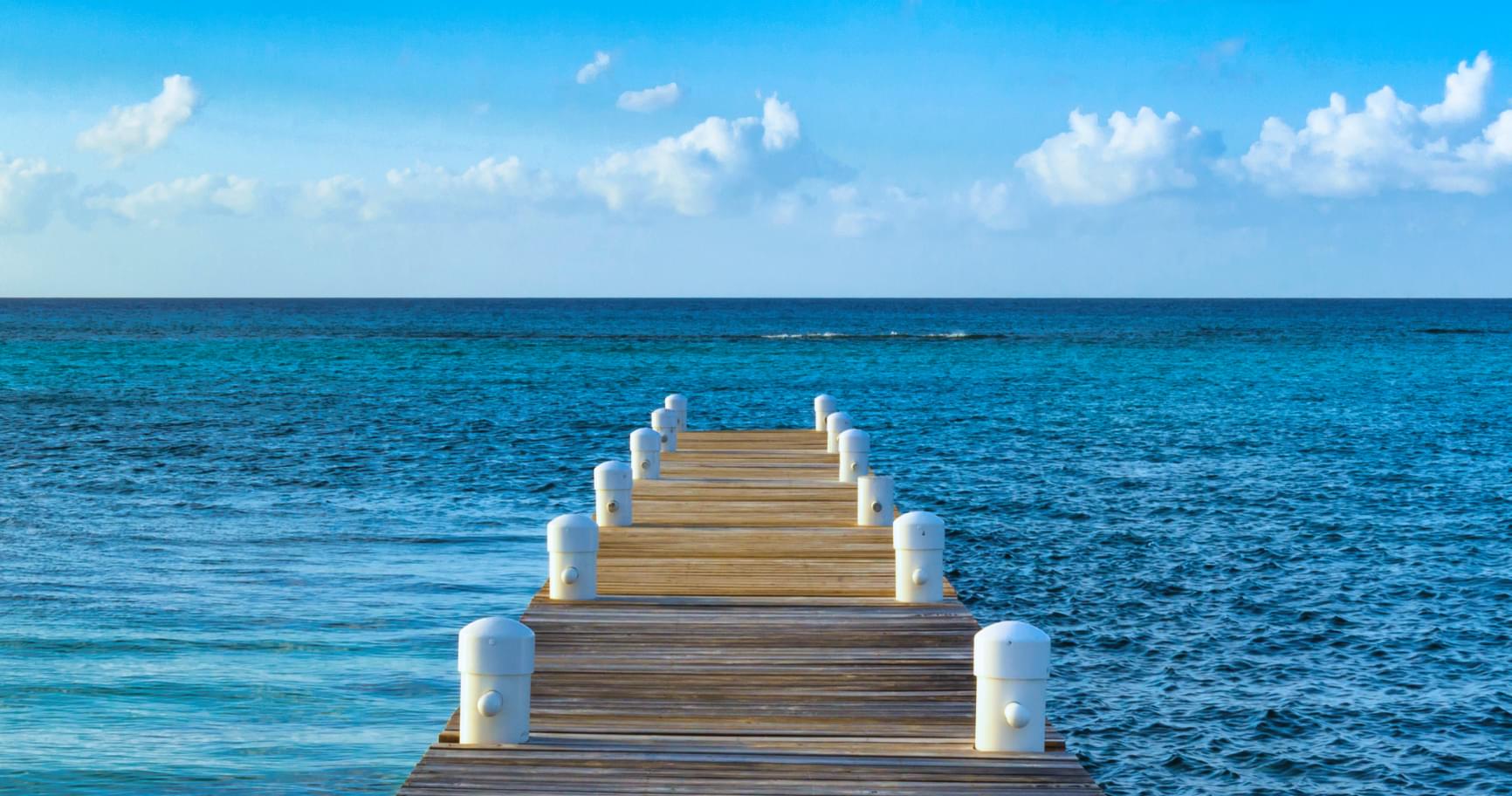 A peaceful dock stretching into clear blue water symbolizes the importance of Grand Cayman entry requirements