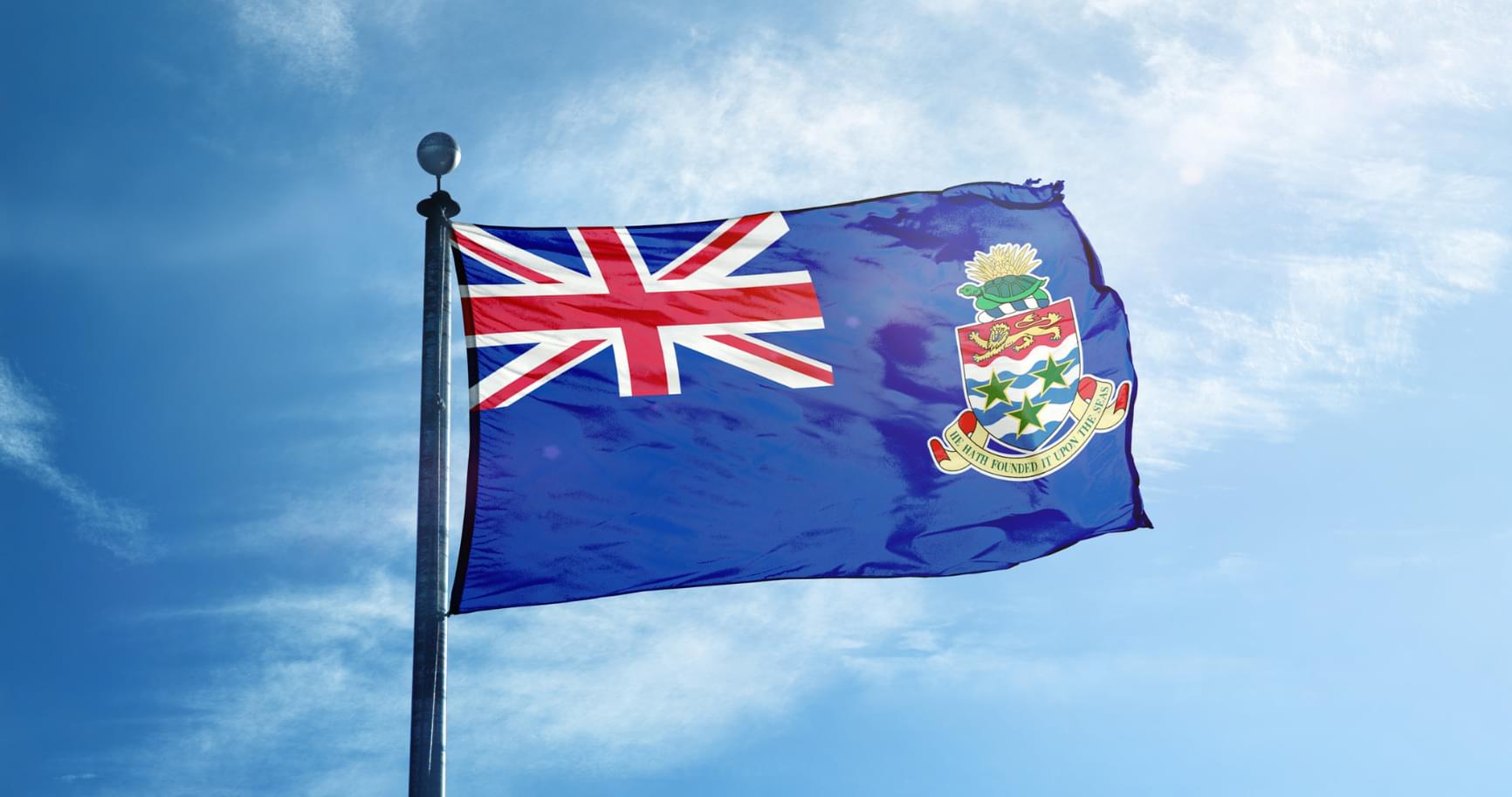The Cayman Islands flag is waving against a blue sky, reflecting national pride and Cayman Islands immigration guidance