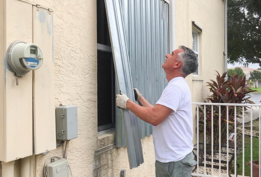 Technicians preparing hurricane shutters, showing proactive safety measures, and ensuring peace of mind for visitors