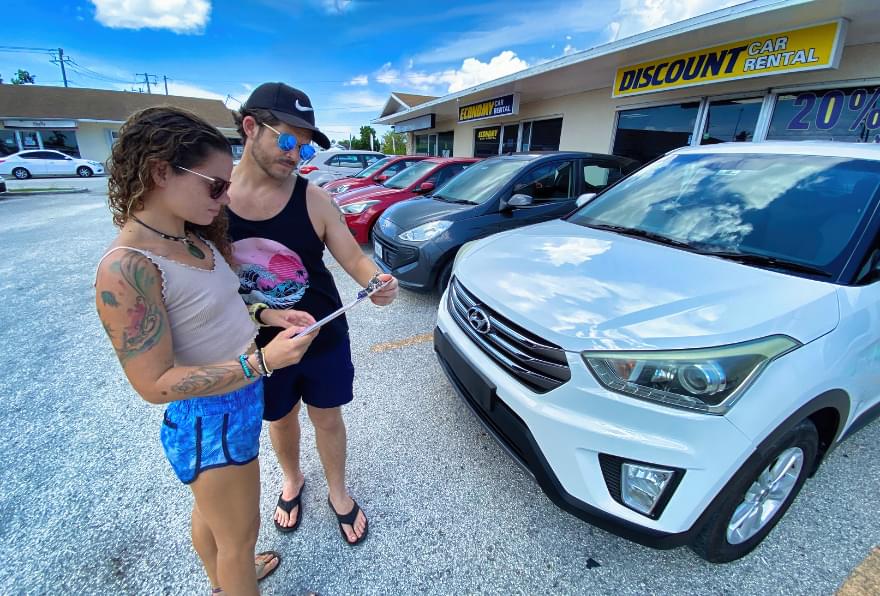 Couple at a car rental office, selecting a vehicle for their adventure
