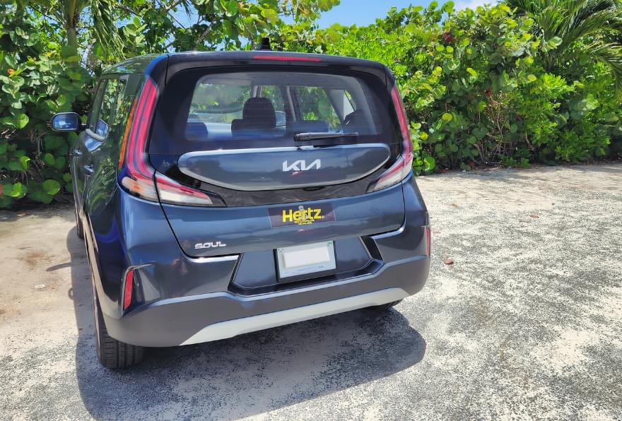 A compact car parked near the beach, representing affordability with Hertz car rental Grand Cayman