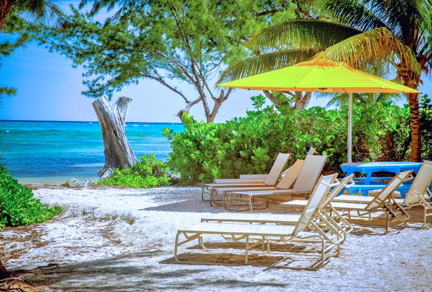 Beach chairs under a shaded area near the Grand Cayman Rum Point