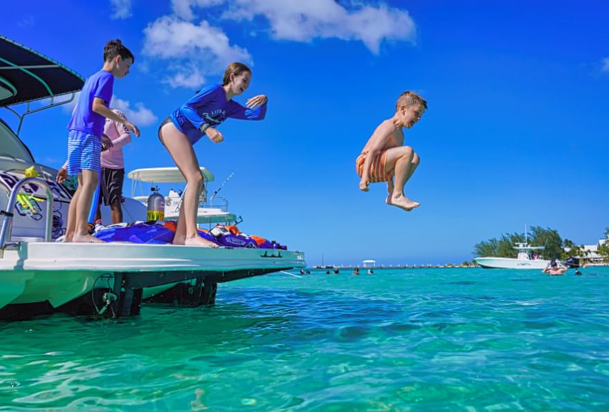 Kids jumping off a ship into clear waters during a cruise to Grand Cayman