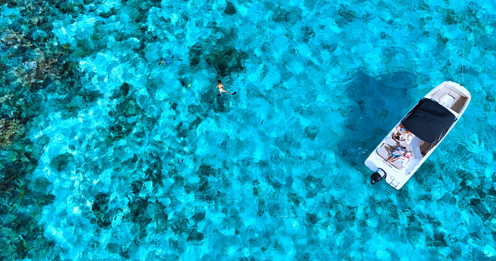 Private boat anchored over a vibrant coral reef near the Grand Cayman area