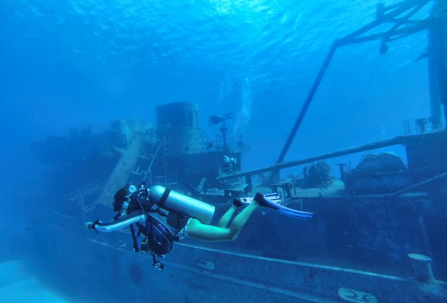 Scuba diver exploring the USS Kittiwake shipwreck near Grand Cayman, a highlight of things to do in Grand Cayman island.