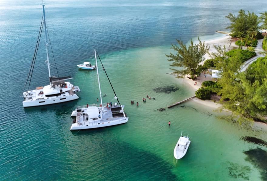 Boats anchored at a serene beach in Grand Cayman, showcasing what to do in the Cayman Islands on the water.