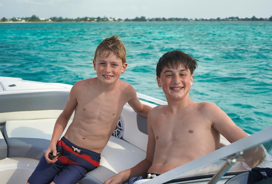 Two boys enjoying a private boat charter, one of the fun things to do in Grand Cayman for families.