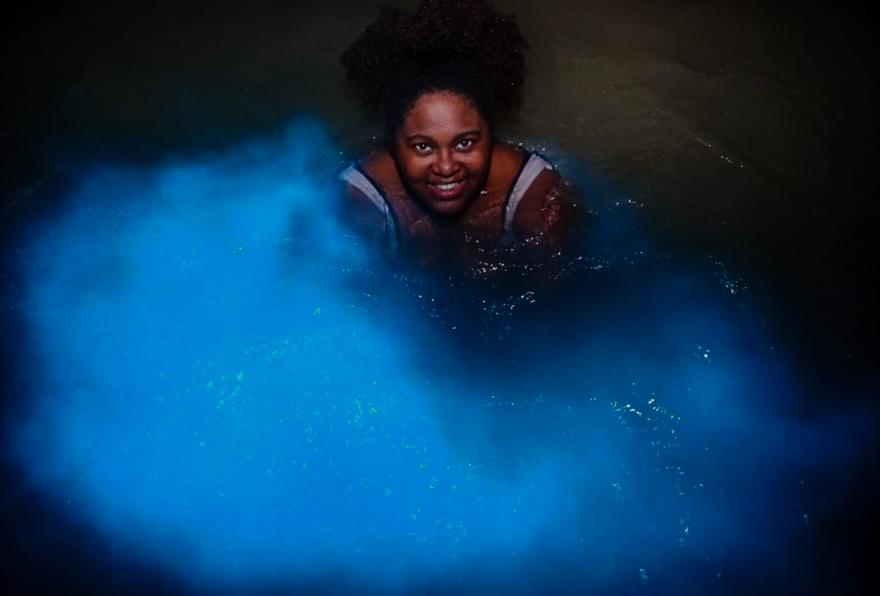 Woman enjoying bioluminescent waters at the Cayman Islands Blue Hole, one of the things to do in the Cayman Islands at night.