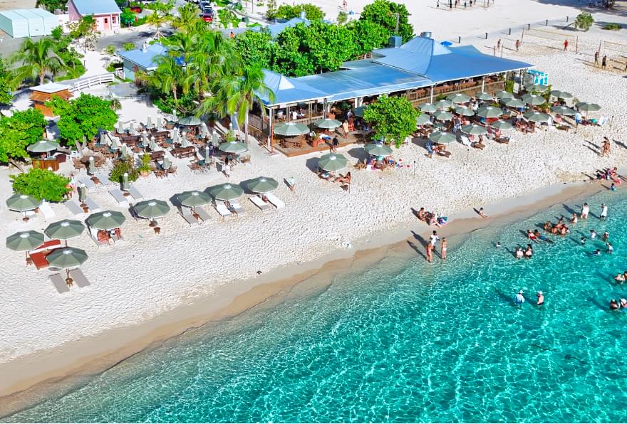 Aerial view of a lively beach bar scene on Seven Mile Beach, Grand Cayman