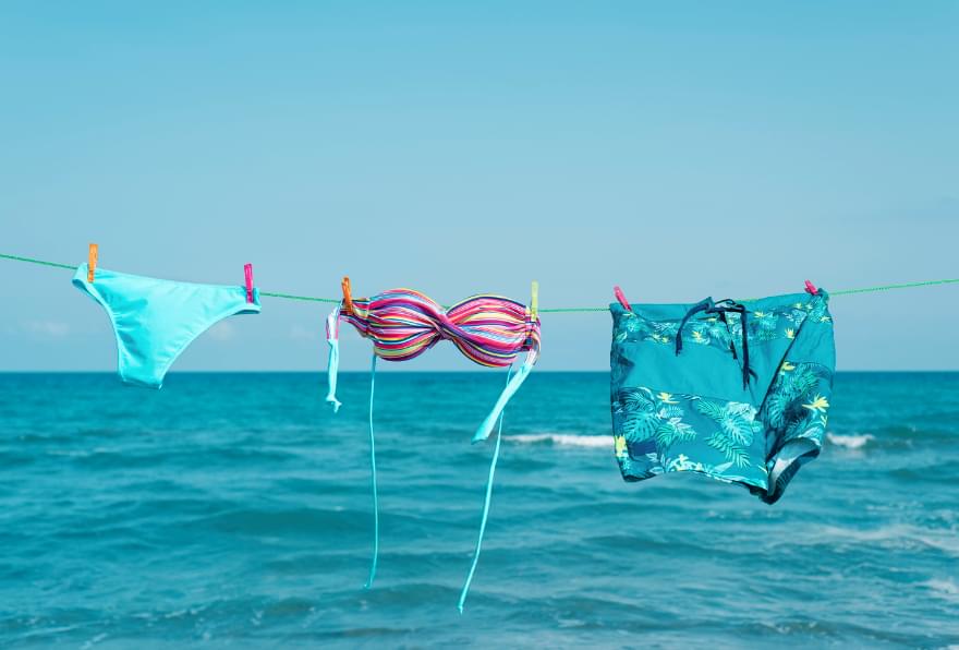 Clothes and swimwear are drying on a line near the ocean, showcasing beachside living in Grand Cayman