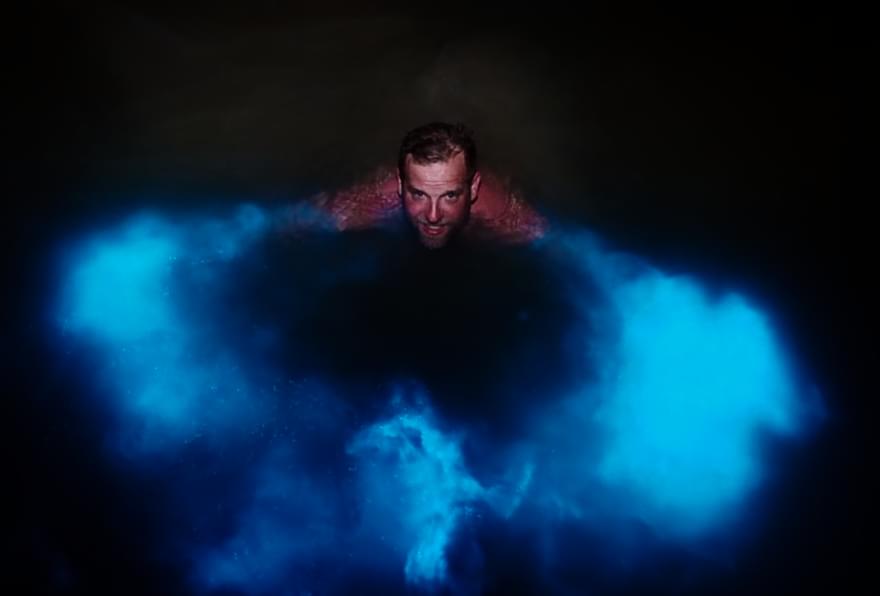 A swimmer experiencing the glowing waters of the Bioluminescent Bay, Grand Cayman, a magical part of night snorkeling Grand Cayman