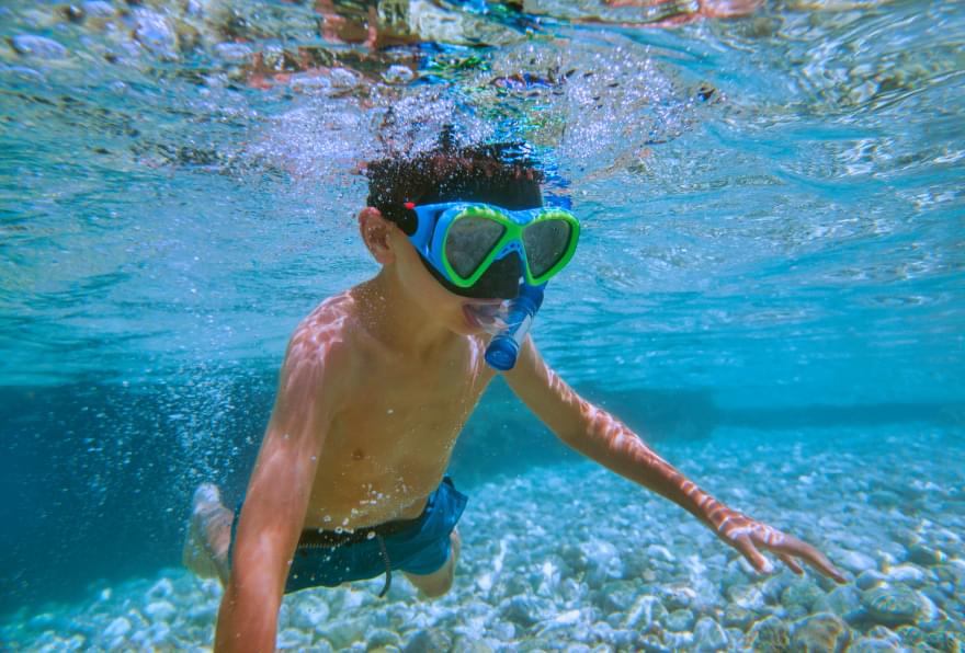 Snorkeler exploring vibrant coral reefs, surrounded by tropical fish in Grand Cayman’s clear waters, a highlight of Cayman snorkeling