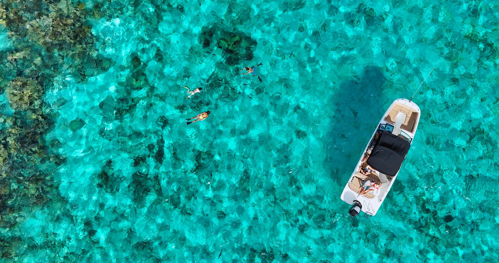 Aerial view of a boat anchored near a reef in Grand Cayman’s turquoise waters