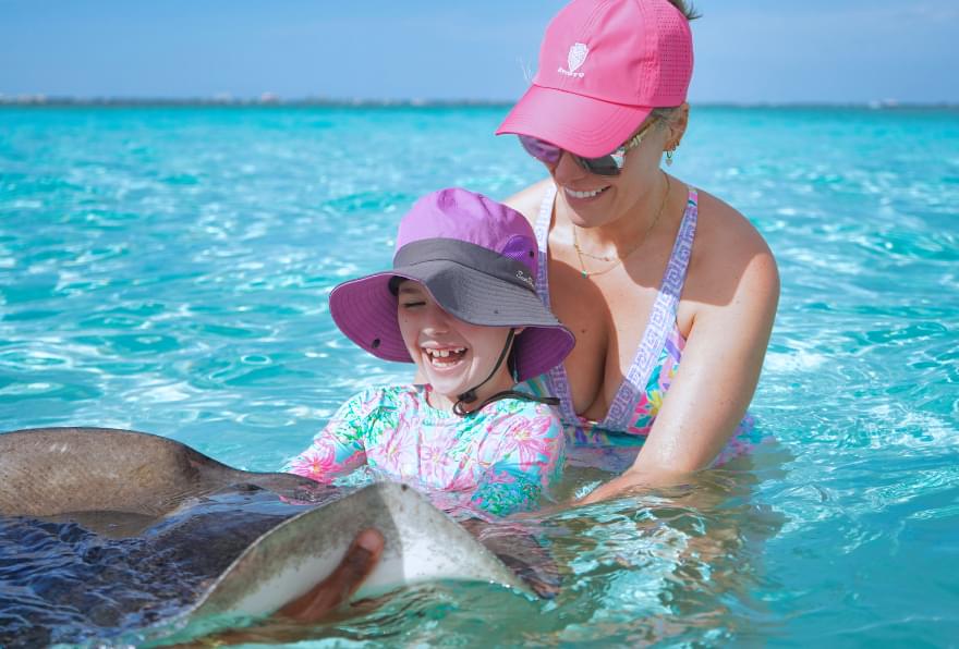 Mother and child at Stingray City, Grand Cayman, interacting with stingrays in a family-friendly Grand Cayman excursion