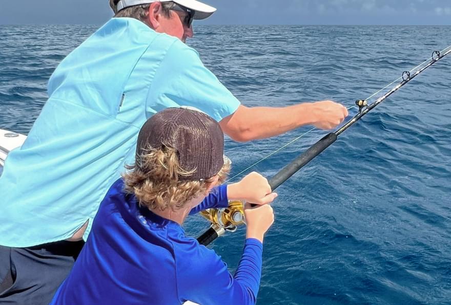 Father and son enjoying deep sea fishing, one of the best cayman island cruise excursions