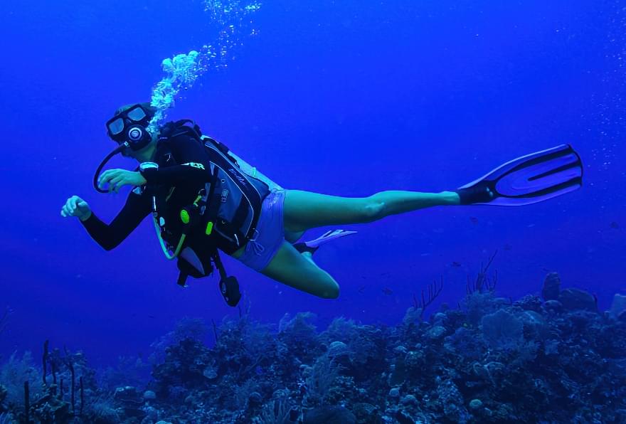 Scuba diving through vibrant coral reefs, a must-try in Cayman Islands snorkeling excursions