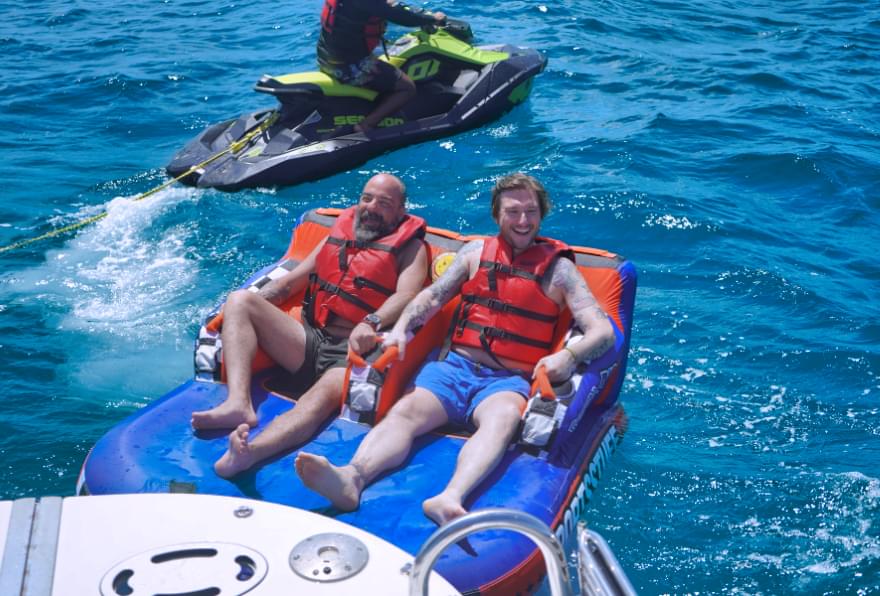 Friends tubing behind a boat during boat trips Cayman Islands, showcasing adventure and fun