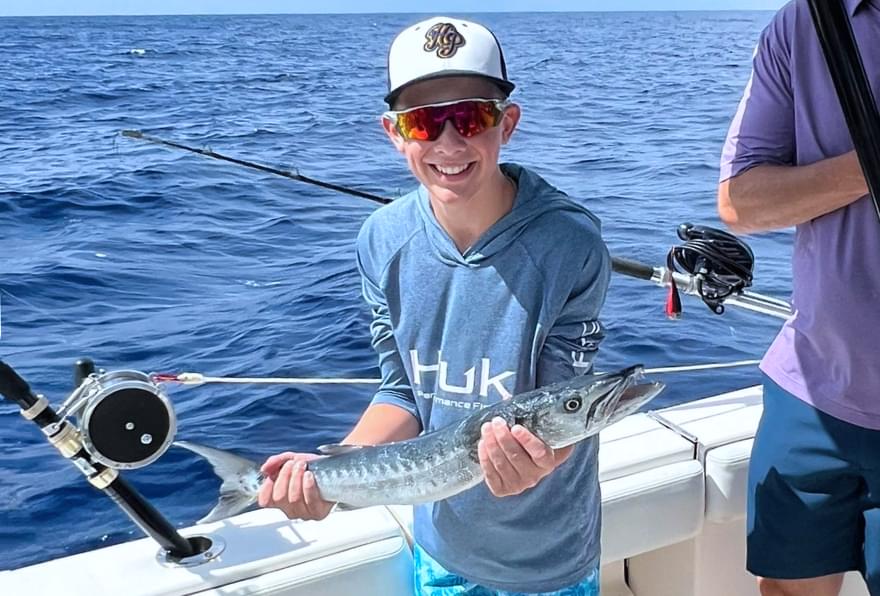 Young angler holding a fish during a deep-sea adventure on a Grand Cayman fishing trip