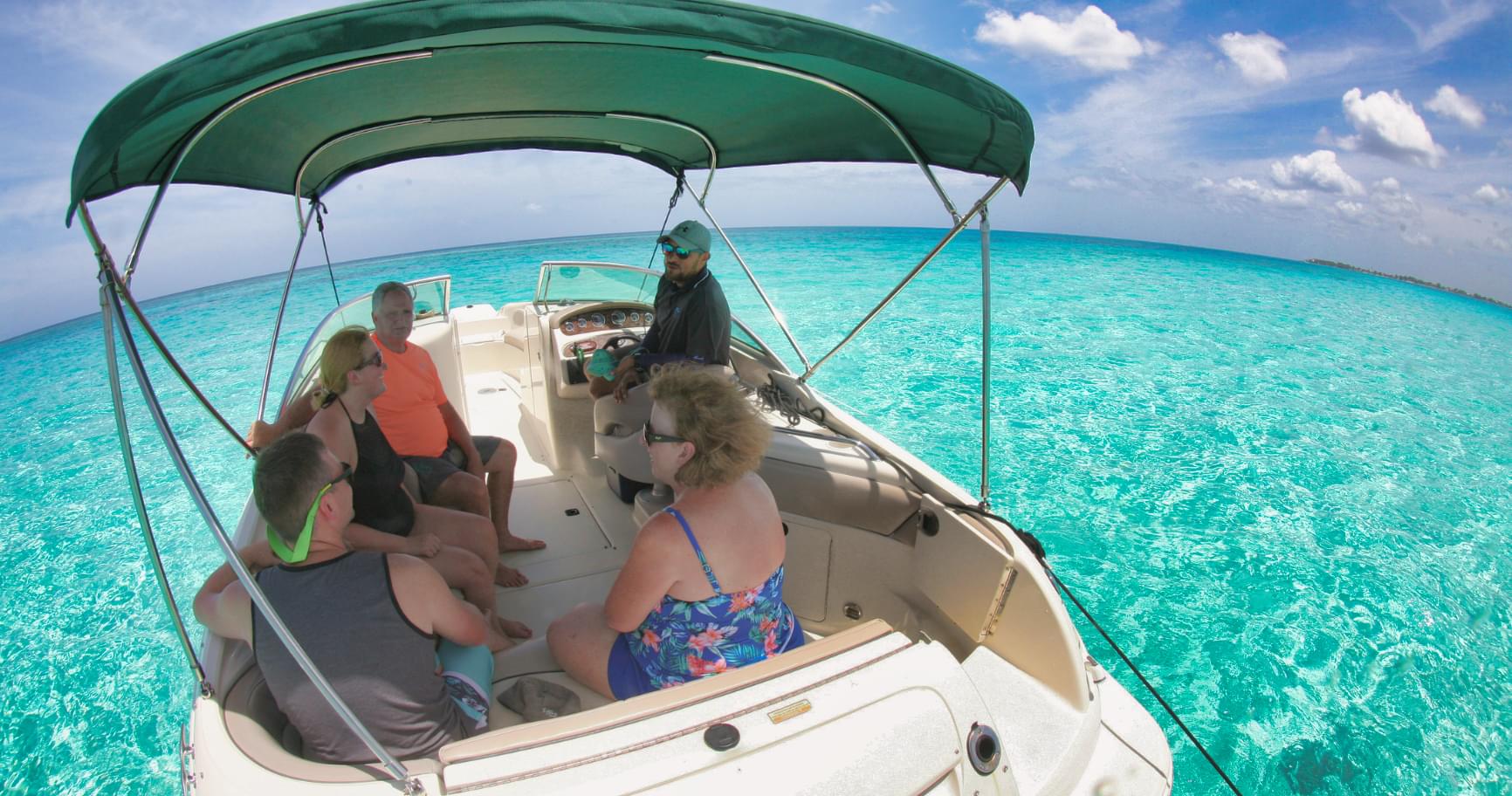 A family is enjoying a shaded private boat ride, showcasing a private boat charter in the Cayman Islands