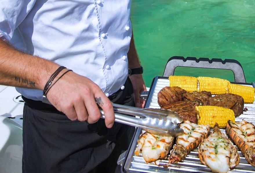 Chef grilling fresh seafood on a yacht, showcasing onboard dining during luxury charters in Cayman