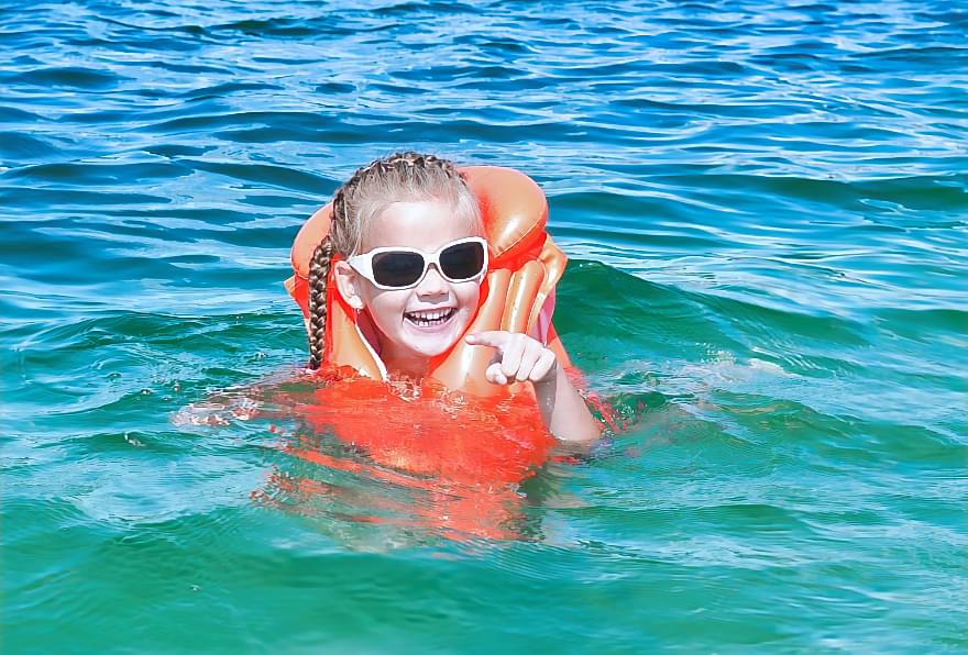 Child swimming safely with a life jacket, emphasizing water safety for children